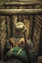 A world war II soldier stands in a wooden trench with a rifle, photo from behind. Royalty Free Stock Photo