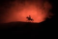 World war officer (or warrior) rider on horse with a sword ready to fight and soldiers on a dark foggy toned background. Battle Royalty Free Stock Photo