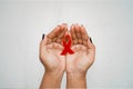 Worlds HIV Aids Day, A top view Closeup hands holding red ribbon emblem aids awareness ribbon on white background