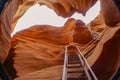 Worm`s eye view of beautiful Lower Antelope canyon. A spectacular orange sandstone cave with white sky and metal stair at the Royalty Free Stock Photo