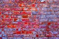 Worn aged brick wall of bright red-pink colour