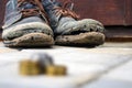 Worn boots with a lagging sole on a background of gray pavers and dark brown wood.