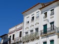 Worn bright facades of white colour downtown at Praca do Giraldo square in Evora, Portugal