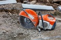 Petrol saw with diamond wheel on construction site gravel in front of concrete parapets