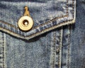 Worn denim patch pocket with button and seams, close up