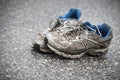 Worn, dirty, smelly and old running shoes on a tarmac road