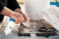 Worn hands of a fisherman cleaning fresh raw fish on a wooden cutting board