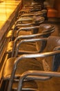 Worn leather bar stools lined up at a bar with light shining on it in a dark room selective focus