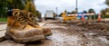 Worn and Muddy Work Boots on Construction Site, Symbolizing Hard Work and Safety Closeup of Leather Boots on a Dirty Ground with Royalty Free Stock Photo