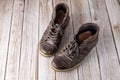 Worn old pair male leather shoes on wooden floor. Brown dirty used male boots