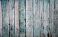 Worn old rough-hewn pine vertical wooden boards with scratches and faded light blue paint.