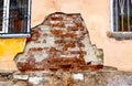 A worn-out building facade with crumbling stucco shows the texture of the red brickwork of the house. Closeup of part of the wall Royalty Free Stock Photo