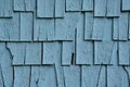 Worn out painted blue cedar shingles. Exterior wall shingle needing replacement.