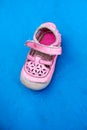 Worn pink children shoe on blue wooden background