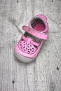 Worn pink children shoe on wooden plank background