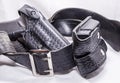 A worn police duty belt with a black pistol and two pistol magazine case wrapped up