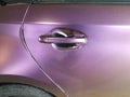 Worn purple wrap on automobile with door handle