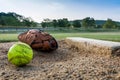 Worn softball and glove on pitcher`s mound in early morning