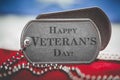 Worn US American dog tags on USA flag with Happy Veteran`s Day engraved text Royalty Free Stock Photo