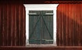 A worn window covered with green wooden shutters