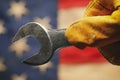 Worn work glove holding wrench tool above US American flag. Made in USA, American workforce, blue collar worker, or Labor Day Royalty Free Stock Photo