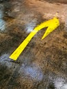 Worn Yellow Turn Right Sign on Wet Car Park Floor