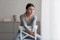 Worried anxiety unhappy pretty caucasian millennial woman sitting on chair and looking out the window