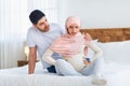 Worried arab husband supporting pregnant wife with prenatal contractions, sitting together on bed, copy space