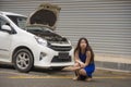 Worried Asian Chinese woman in stress stranded on roadside with car engine failure having mechanic problem needing repair service Royalty Free Stock Photo