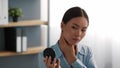 Worried Asian Woman Scratching Neck Suffering From Itchiness In Office