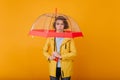 Worried beautiful girl with short hair standing under umbrella. Studio portrait of upset caucasian woman in raincoat