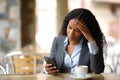 Worried black businesswoman checking phone in a bar Royalty Free Stock Photo