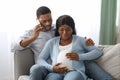 Worried black man calling doctor while wife having labor pains