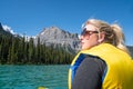 Worried blonde woman looks out in the distance, thinking and reflecting while canoeing on Emerald Lake in Yoho National Park