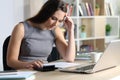 Worried bookkeeper looking at calculator at homeoffice