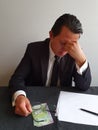 worried businessman with hand on his face and Chilean money on the table