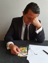 worried businessman with hand on his face and swiss money on the table