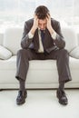 Worried businessman with head in hands sitting on couch Royalty Free Stock Photo