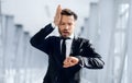 Worried businessman looking at his watch and touching his head Royalty Free Stock Photo