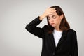 Worried businesswoman in a sleek black suit with her hand on her forehead displaying a gesture of forgetfulness