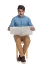 Worried casual man reading a newspaper and frowning Royalty Free Stock Photo