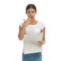 Worried casual woman reading newspaper and covering her mouth Royalty Free Stock Photo