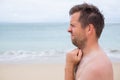 Worried caucasian man sucking his thumb standing on the tropical beach