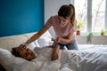Worried caucasian mother measuring temperature of sick teen daughter lying in bed Royalty Free Stock Photo