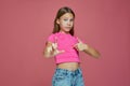 Worried child girl pointing by fingers on herself and showing amount size gesture, standing on pink studio background Royalty Free Stock Photo