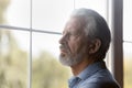 Worried concerned elderly male pensioner stand alone look through window