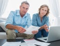 Worried couple paying their bills online with laptop looking at Royalty Free Stock Photo