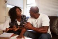 Worried Couple Sitting On Sofa Arguing About Bills