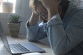 Worried and desperate stressed worker an at the desk holding his head with exhausted expression. Side view of businessman small Royalty Free Stock Photo