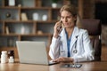 Worried Doctor Woman Using Laptop And Talking On Cellphone At Workplace Royalty Free Stock Photo